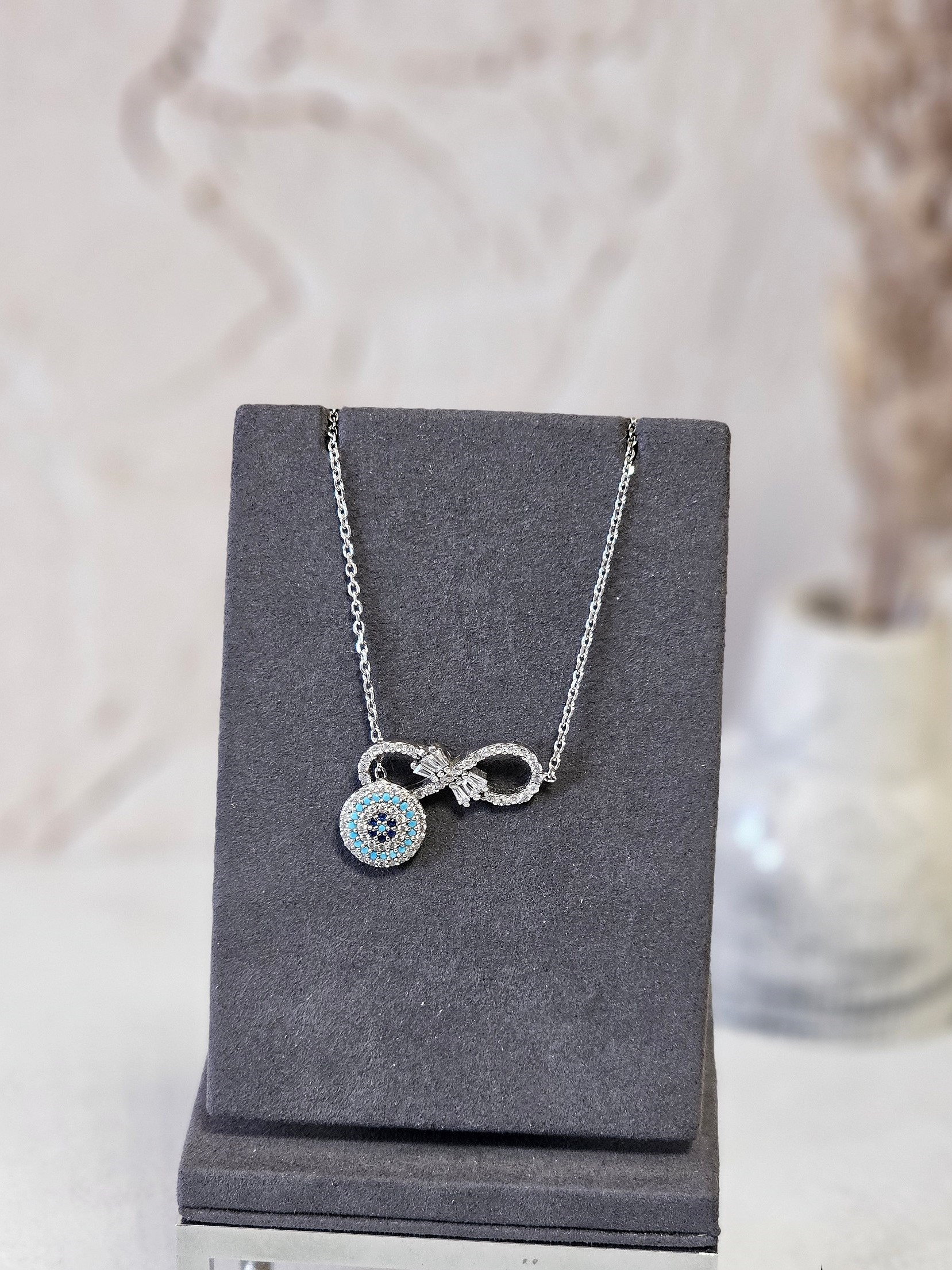 زنجیر نقره با پلاک متصل بینهایت و آویز چشم نظر با نگین های آبی روشن و تیره